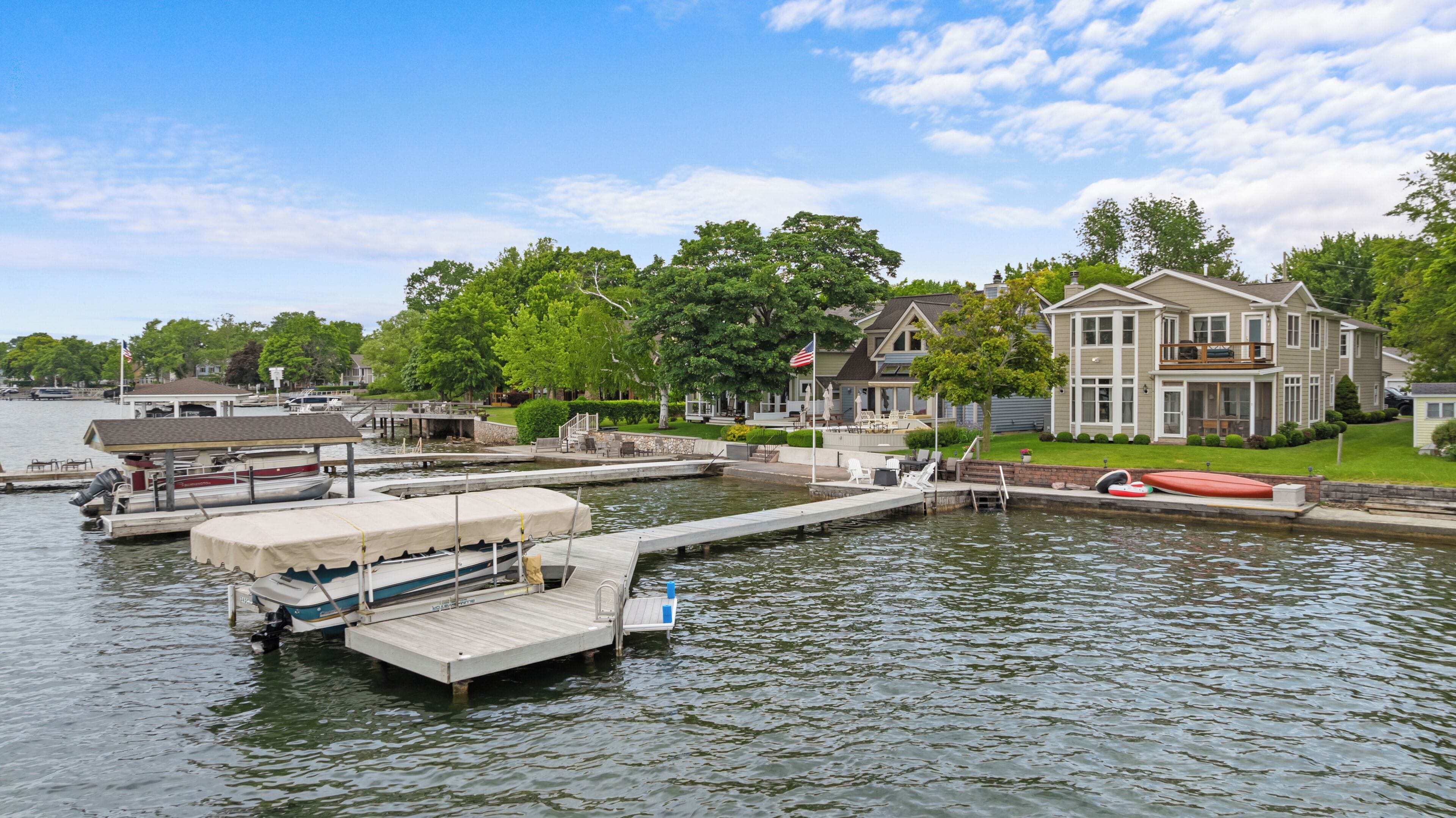 Une propriété située au bord de l’eau, dotée d’un quai, d’une maison avec balcon et d’un bateau.