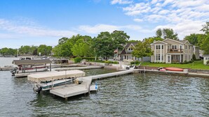 Ein Anwesen am Wasserufer mit Anlegesteg, ein Haus mit Balkon und ein Boot.
