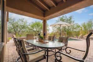 An outdoor patio with a glass-top table, cushioned chairs, a pool, and a pergola with an umbrella. - 4BR The Talon Trail Home: Pool, Spa,  Golf Access (Scottsdale)