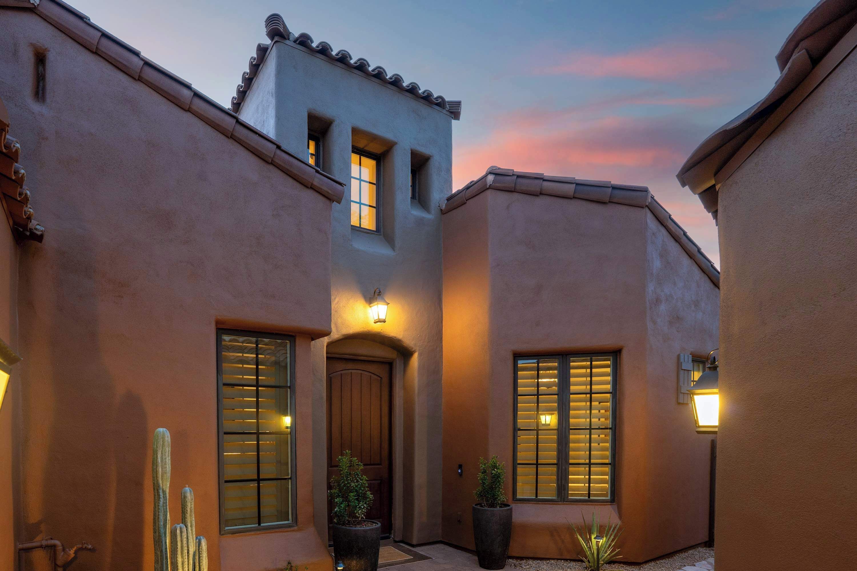 A building with a stucco exterior, a wooden door, and multiple windows with shutters.