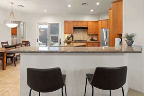 A modern kitchen with granite countertops, wooden cabinets, and a stainless steel refrigerator. - 4BR The Talon Trail Home: Pool, Spa,  Golf Access (Scottsdale)