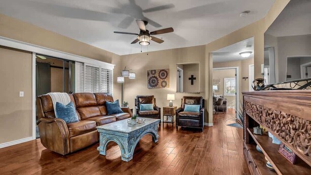 A spacious living room with a brown leather sofa, two armchairs, a coffee table, and a wooden sideboard. - Beautiful pool oasis near TPC Scottsdale (Scottsdale)