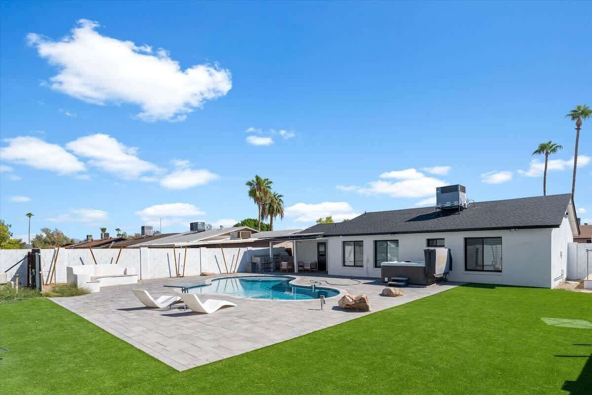 Una casa moderna con piscina, patio y césped bien cuidado.