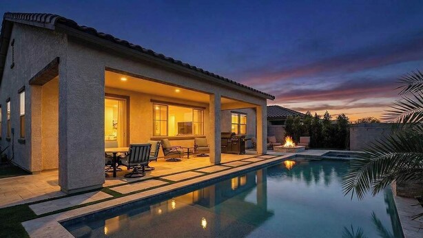 Una casa moderna con piscina, mobiliario exterior y un patio.