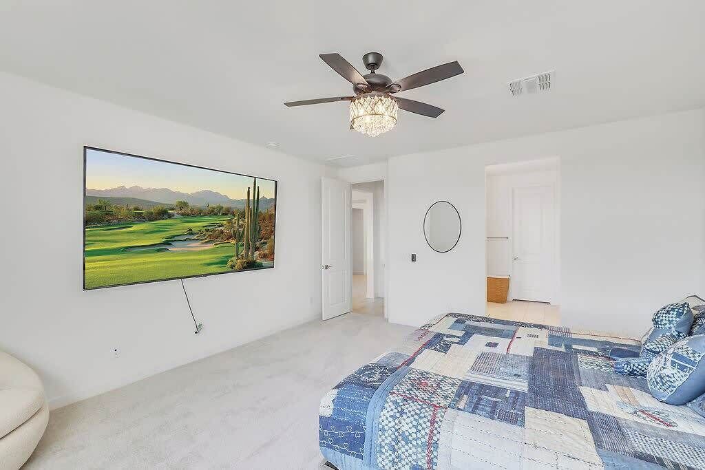 Une chambre dotée d’une grande télévision, d’un ventilateur de plafond, d’une couvre-lit matelassé et d’une porte donnant sur une autre pièce.