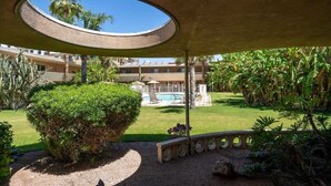 Ein Innenhof mit Pool, Palmen und einer runden Aussichtsplattform.