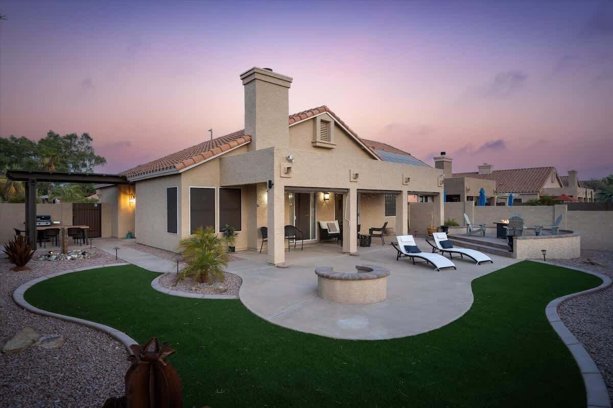 A modern house with a patio, outdoor seating, and a well-maintained lawn.