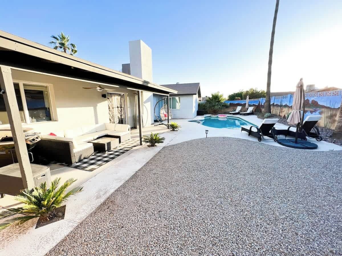 A modern house with a pool, outdoor seating, and a covered patio.