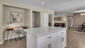 A modern kitchen with a central island, white cabinetry, and a dining area with a table and chairs. - Exclusive retreat- Heated pool & BBQ grill (Peoria)