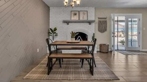 A dining area with a wooden table and chairs, a chandelier, and a fireplace. - Exclusive retreat- Heated pool & BBQ grill (Peoria)