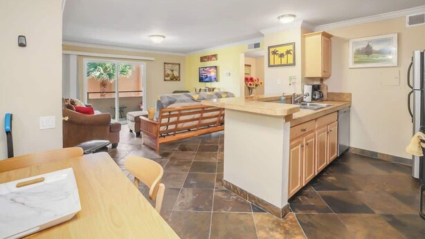 Un espacio habitable compacto con cocina, comedor y una pequeña zona de estar con sofá y banco de madera.