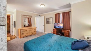Un dormitorio con cama, cómoda, televisor y armario.