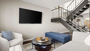 Ein modernes Wohnzimmer mit Flachbildfernseher, Treppe und Sofa.