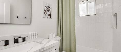 Une salle de bain moderne avec un meuble-lavabo blanc, des toilettes et une baignoire.