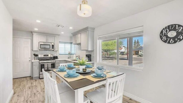 A modern kitchen with white cabinets, a microwave, and a dining area with a table set for four. - Historic Coronado retreat with outdoor fire pit (Phoenix)