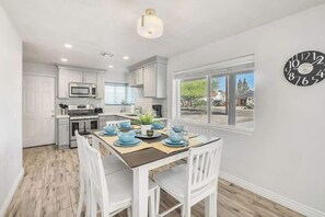 A modern kitchen with white cabinets, a microwave, and a dining area with a table set for four. - Historic Coronado retreat with outdoor fire pit (Phoenix)