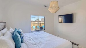 Een slaapkamer met een bed, een aan de muur bevestigde televisie en een raam met uitzicht.