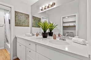 A modern bathroom with a white vanity, two sinks, a large mirror, and decorative plants. - Spa, BBQ & Fire Pit | Minutes to Downtown (Flagstaff)