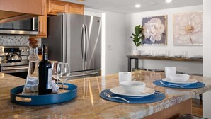 A modern kitchen with stainless steel appliances, a marble countertop, and a dining area with a table set for two. - Private pool + fire pit · Moon Valley retreat (Phoenix)