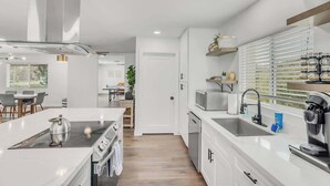 A modern kitchen with white cabinetry, a central island, and a built-in oven. - Golf course view: pool, ping pong, fire pit (Scottsdale)
