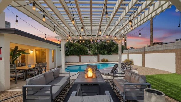 An outdoor patio with a fire feature, seating, and a pool in the background. - Golf course view: pool, ping pong, fire pit (Scottsdale)