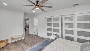 A bedroom with a bed, a ceiling fan, a bench, and a wardrobe with frosted glass doors. - Golf course view: pool, ping pong, fire pit (Scottsdale)
