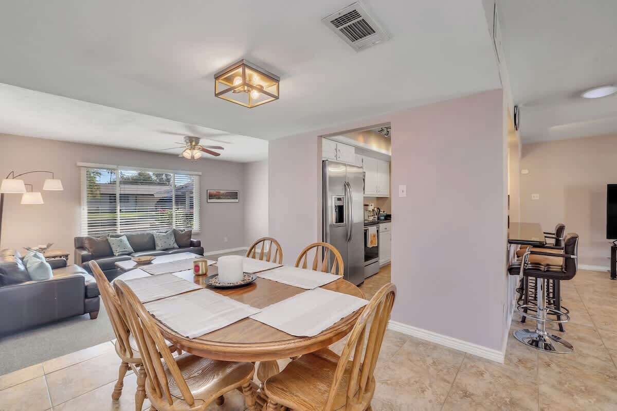 A modern living room with a dining table, sofas, and a kitchen area.