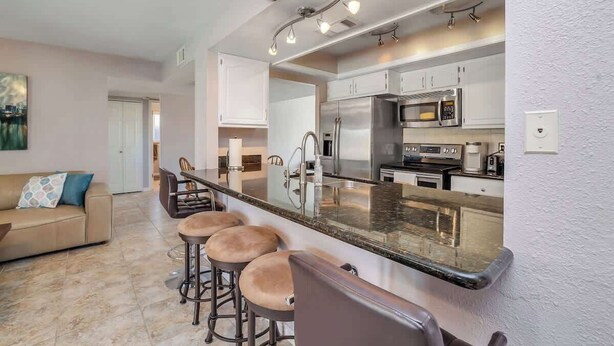 A modern kitchen with a central island, stainless steel appliances, and a dining area with bar stools. - Exclusive Tempe home: pool, BBQ, sleeps 8 (Tempe)