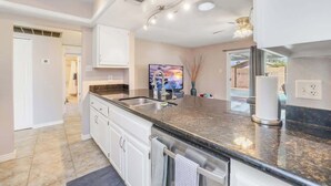 A modern kitchen with a granite countertop, stainless steel sink, and white cabinetry. - Exclusive Tempe home: pool, BBQ, sleeps 8 (Tempe)