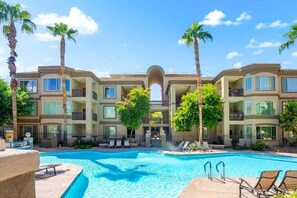 A hotel with a swimming pool, palm trees, and a clear blue sky. - Exclusive lakefront condo | Pool & trails (Tempe)