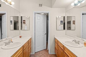 A bathroom with two sinks, wooden cabinets, and large mirrors. - Exclusive lakefront condo | Pool & trails (Tempe)