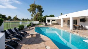A modern outdoor pool area with lounge chairs and a dining table. - Exclusive Golf Retreat: Pool, Spa, Sleeps 18 (Phoenix)