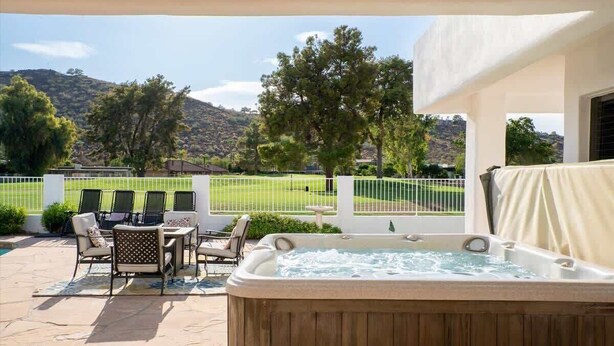 A hot tub with a patio area, outdoor seating, and a view of a golf course and hills. - Exclusive Golf Retreat: Pool, Spa, Sleeps 18 (Phoenix)