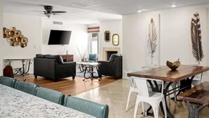 A modern living room with a flat-screen TV, a fireplace, and artwork on the walls. - Exclusive Golf Retreat: Pool, Spa, Sleeps 18 (Phoenix)