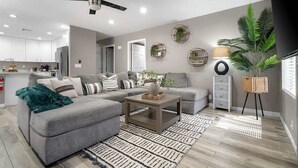 Een moderne woonkamer met een grijze modulaire bank, een houten salontafel en een kamerkleed met dessin.