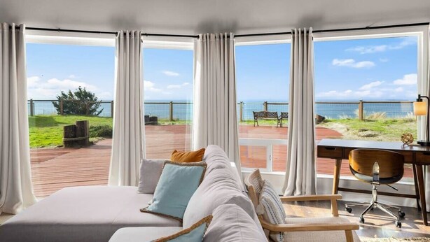 Een slaapkamer met een groot bed, een bureau en uitzicht op zee.