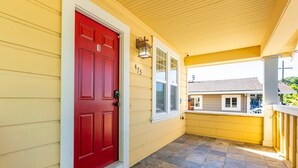 Ein gelbes Haus mit roter Tür, Hausnummer 415, und einer Veranda mit Steinplatten.