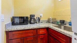 Eine Küche mit Granitarbeitsplatten, einer Mikrowelle, einer Kaffeemaschine, einem Toaster und Holzausbau.