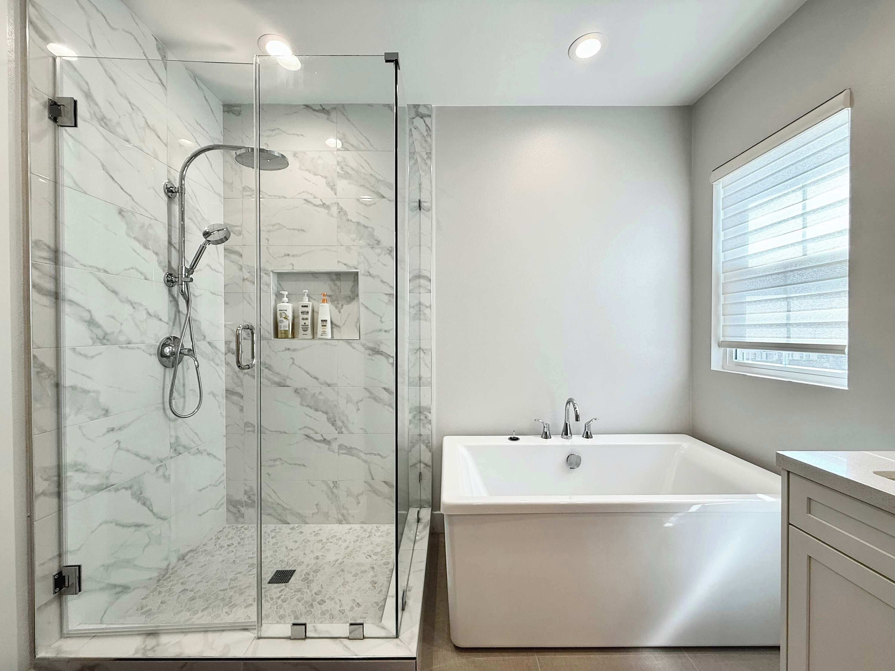 Un baño moderno con ducha de vidrio, bañera independiente y tocador con ventana.