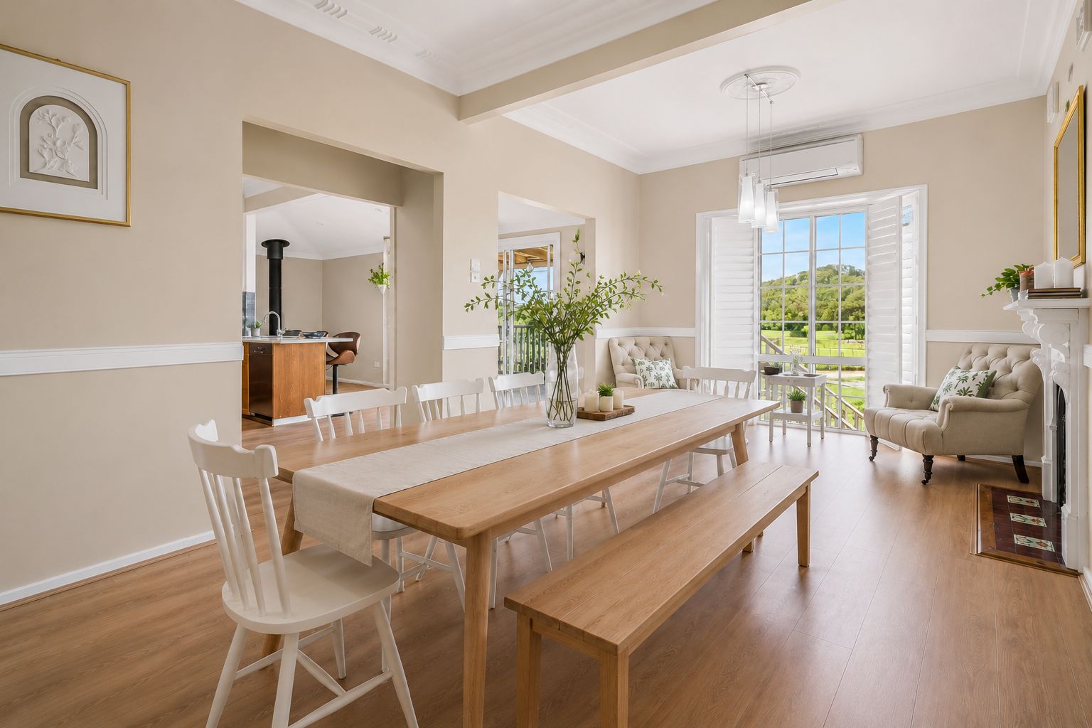 Une salle à manger spacieuse avec une longue table en bois, des chaises blanches et une cheminée.