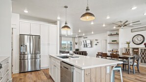 A modern kitchen with white cabinetry, stainless steel appliances, and a central island.