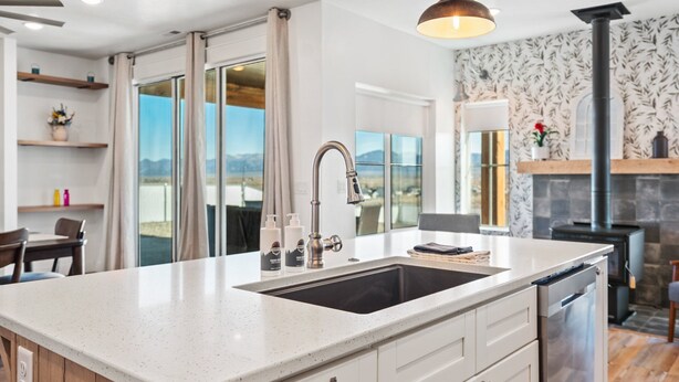 A modern kitchen with a large island, stainless steel appliances, and a view of the outdoors.