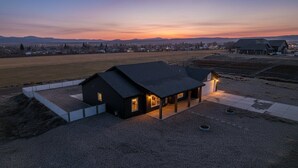 A modern house with a dark roof, a covered porch, and a gravel driveway.