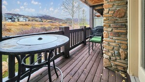 Een overdekt terras met een stenen muur, een tafel en stoelen.
