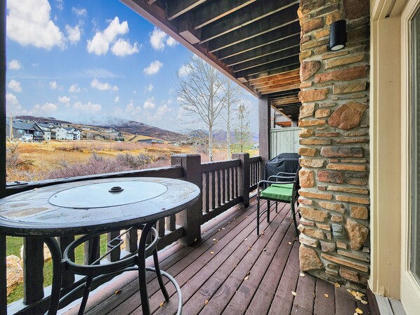 Une terrasse couverte avec un mur en pierre, une table et des chaises.