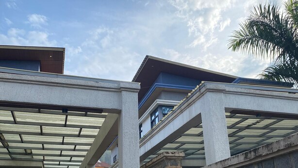 A covered outdoor area with a stone wall and a car parked nearby. - KIGALI QUEENS HOME AND APRTMENTS (Kigali)