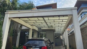 A modern building with a covered driveway and a parked car. - KIGALI QUEENS HOME AND APRTMENTS (Kigali)