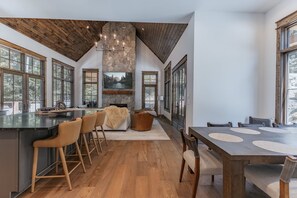 A spacious kitchen with a large island, wooden flooring, and a stone accent wall. - Luxe Eagles Nest Home: Hot Tub, 2 Outdoor Fireplaces & Fire Pit; Views (Banner Elk)