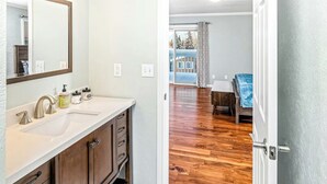 A bathroom with a large mirror, two sinks, and wooden cabinets. - Spacious Home • Hot Tub • Sleeps 24 • Near Airport (Anchorage)