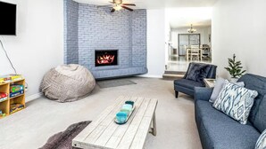 A living room with a fireplace, a sofa, a coffee table, and a bookshelf. - Spacious Home • Hot Tub • Sleeps 24 • Near Airport (Anchorage)